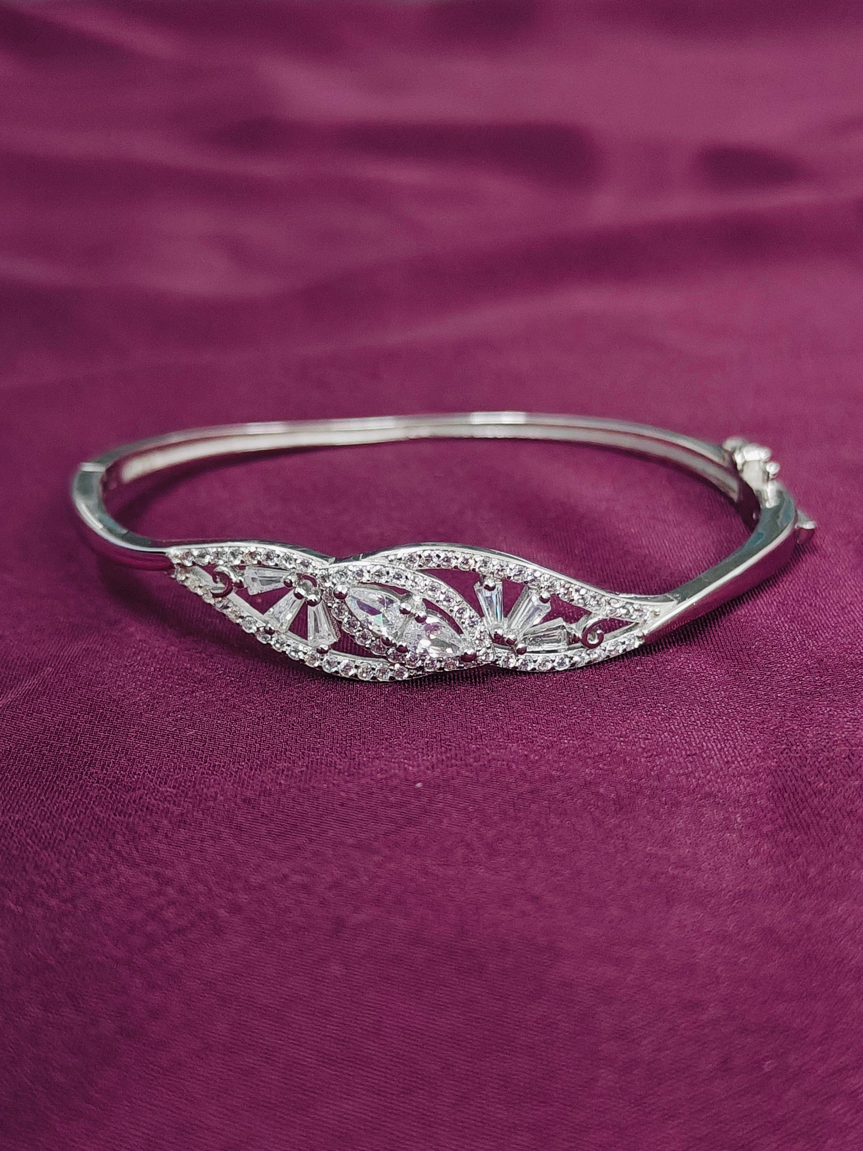 Silver bracelet with intricate design on a purple fabric background